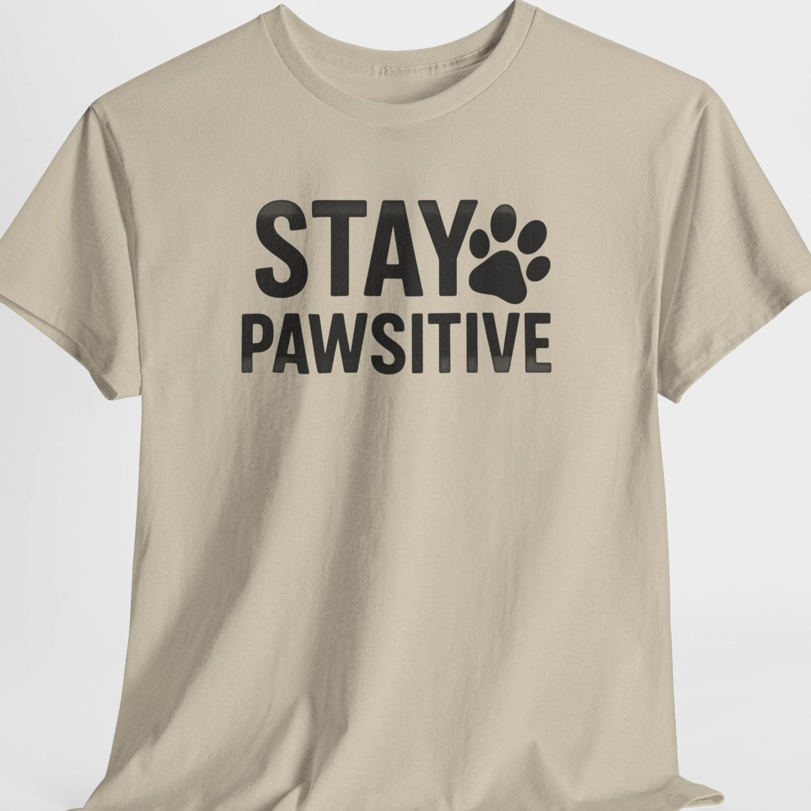 Beige t-shirt with 'Stay Pawsitive' text on a white background