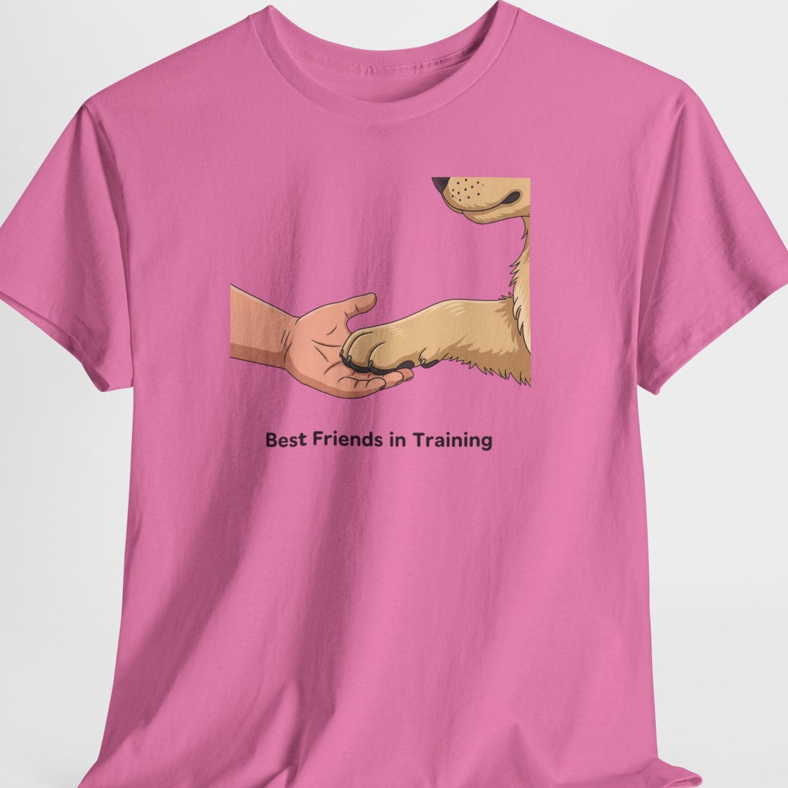 Pink t-shirt with a graphic of a hand shaking a dog's paw and text 'Best Friends in Training' on a white background.