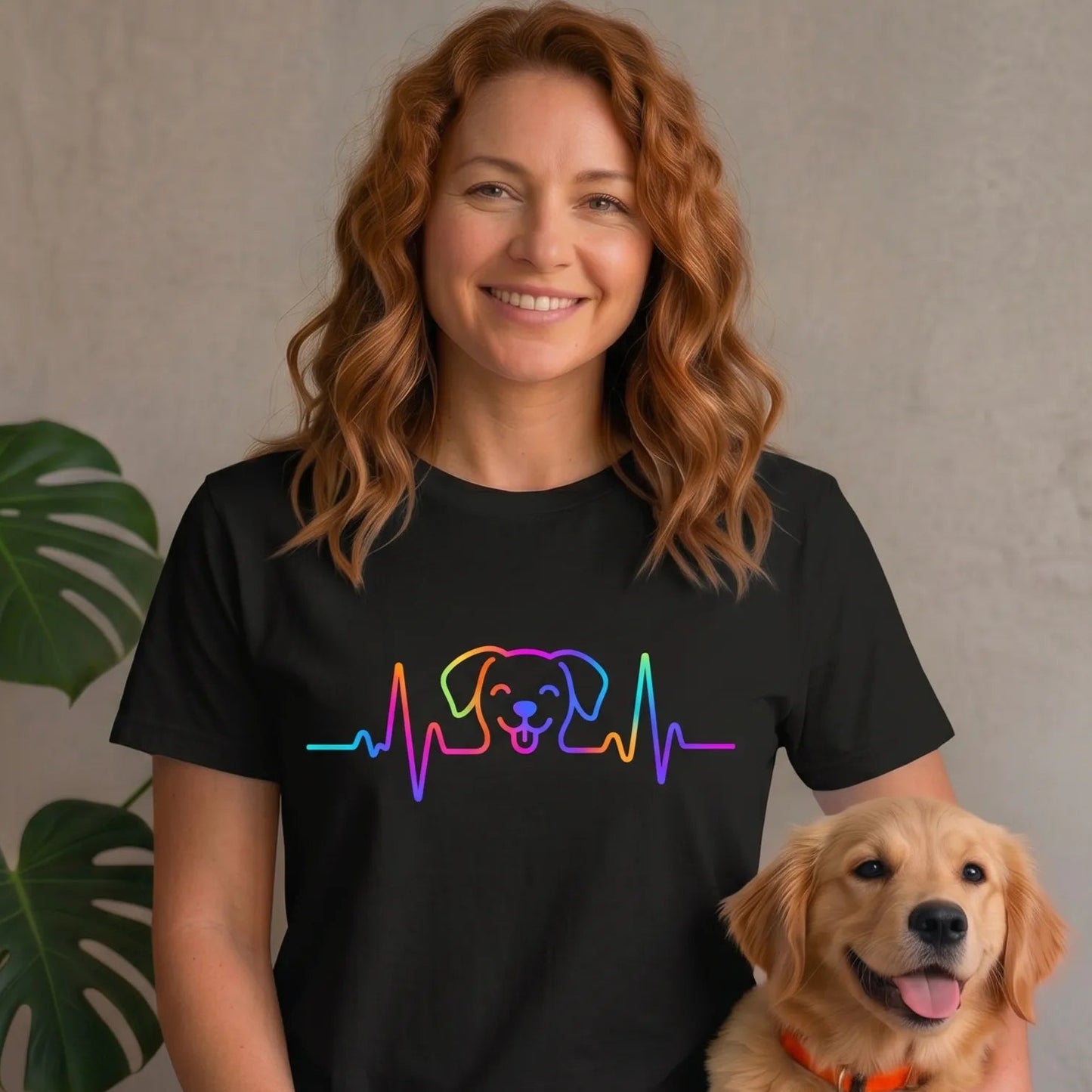 Woman wearing a black t-shirt with a colorful dog heart rate ekg design, sitting with a golden retriever.